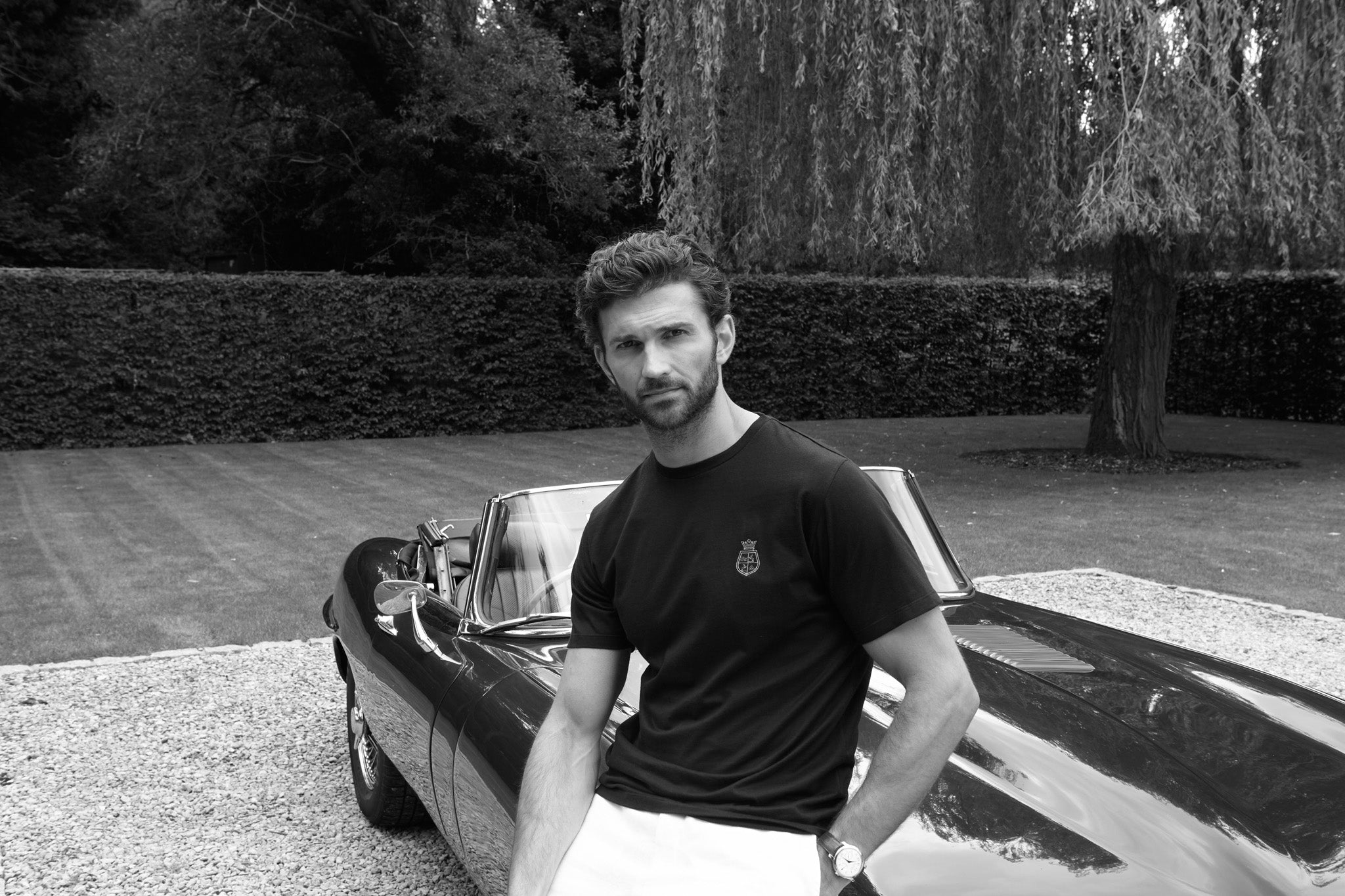 Man leaning against car wearing the black t shirt with real 24ct gold embroidery 