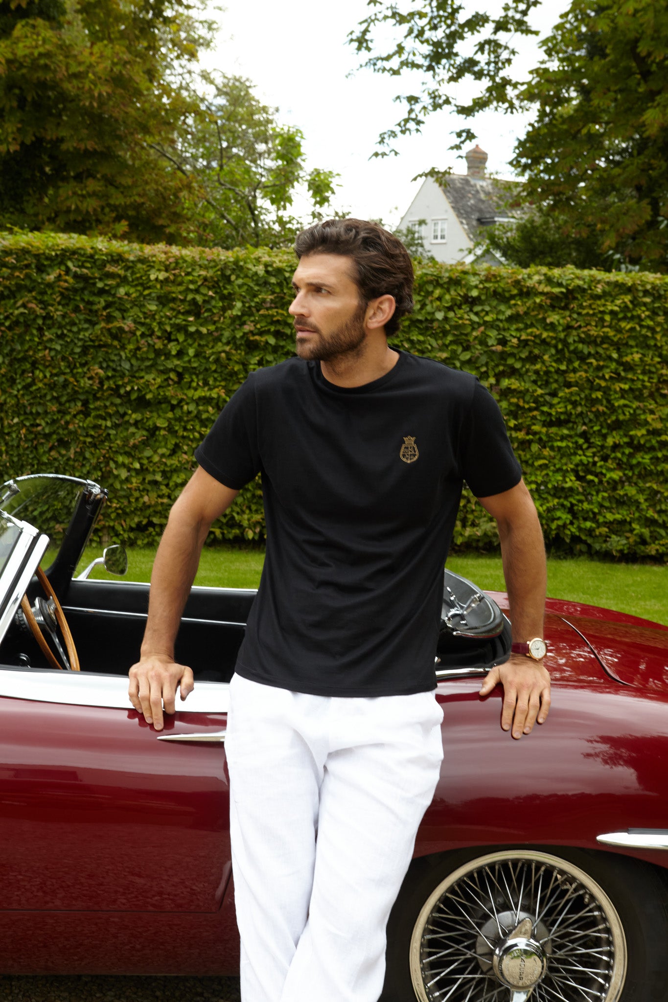 Man leaning against car wearing the black t shirt with real 24ct gold embroidery 