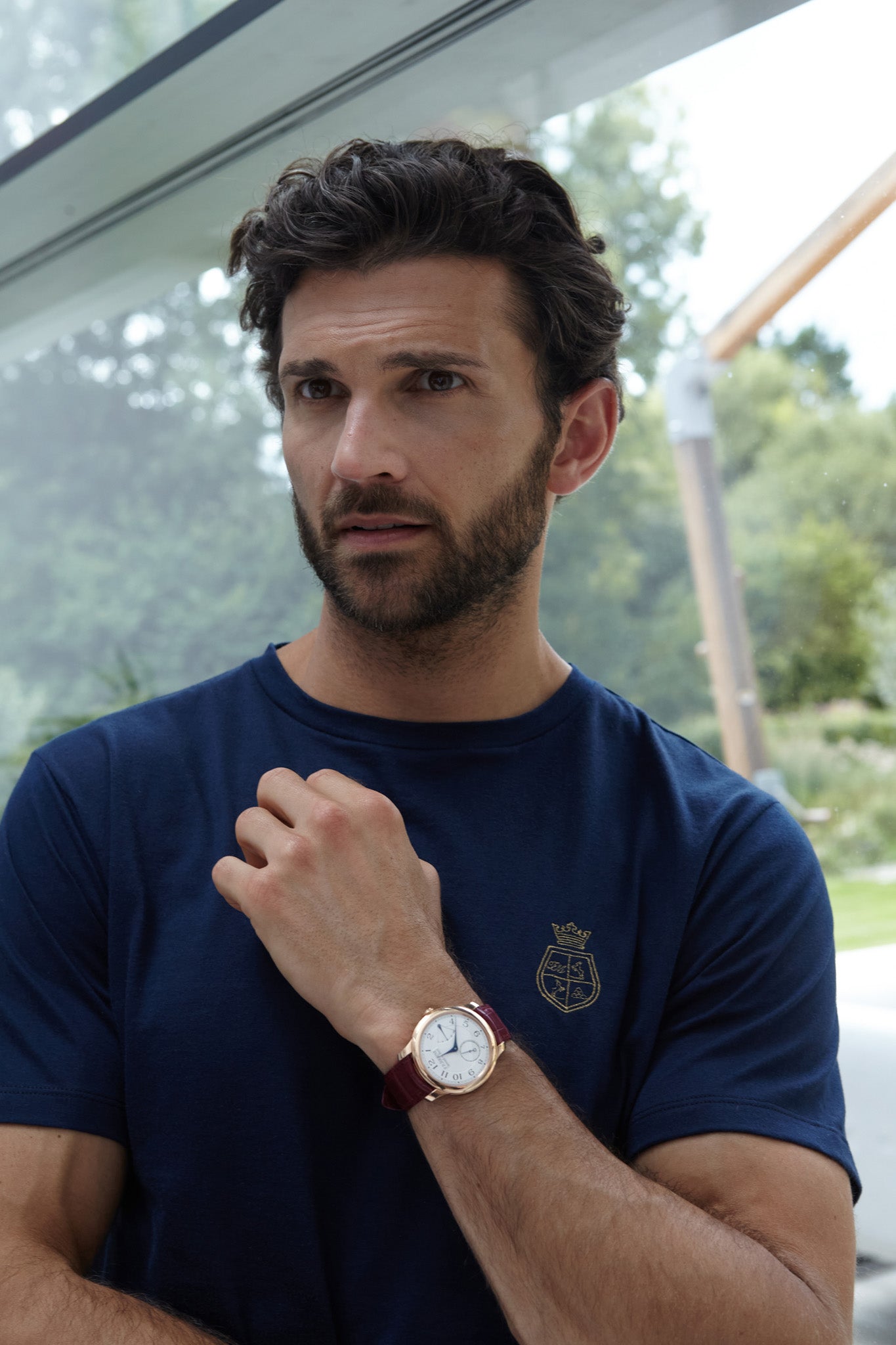 man leaning again window wearing an F.P. Journe with a t shirt with solid gold